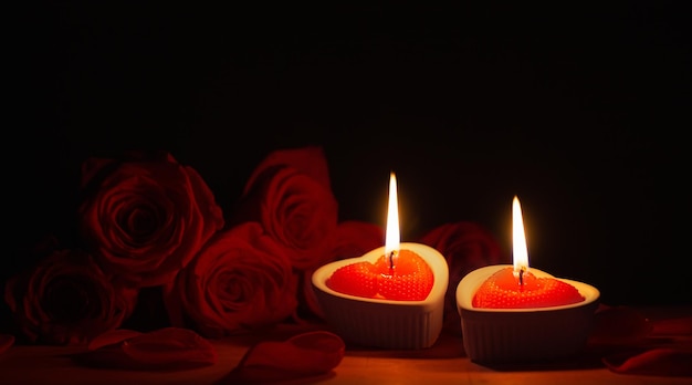 Red roses with burning candles on dark background