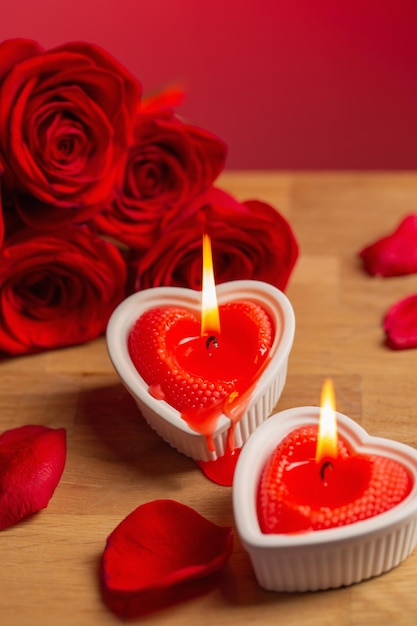 Red roses with burning candles on red background