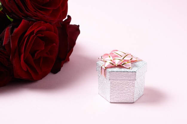 red roses with gift box on pink. copy space. romance and love concept