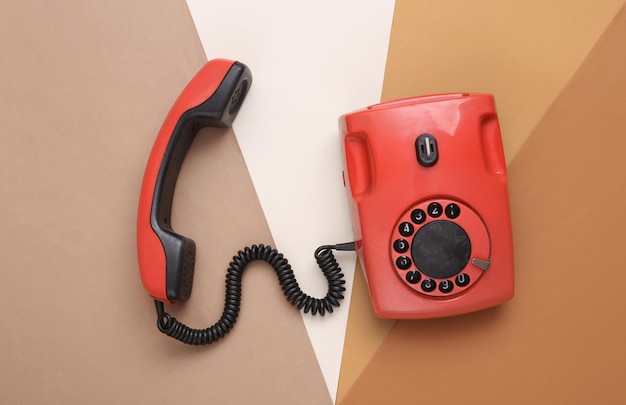 Red rotary retro telephone on a colored background Top view