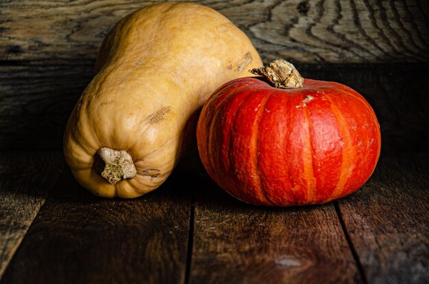 Red round and yellow oblong pumpkin on the background of old wooden boards.