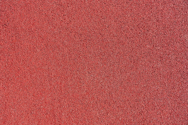 Photo red rubber coating made of recycled rubber chips on the sports field.top view