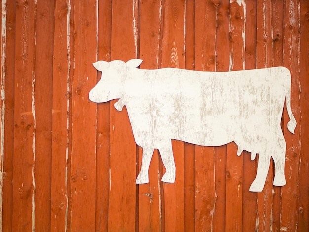 Red rustic wooden barn facade with cow stencil for text farming concept