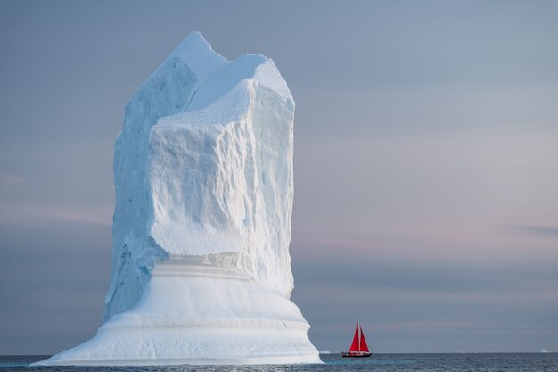 Red sail with large glacier and iceberg