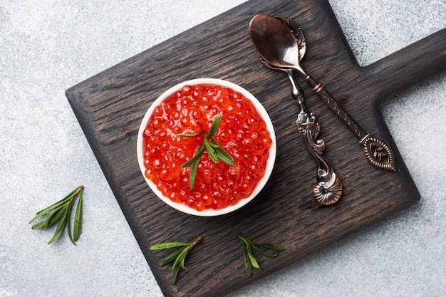 Red salmon caviar in a plate on a wooden cutting Board.