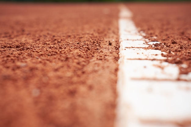 Red sand tennis field with white line close background