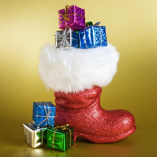 Red Santa boot and gifts on gold background