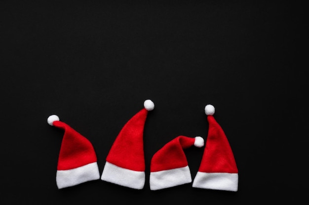 Red santa caps on a black background. New Year concept photo.