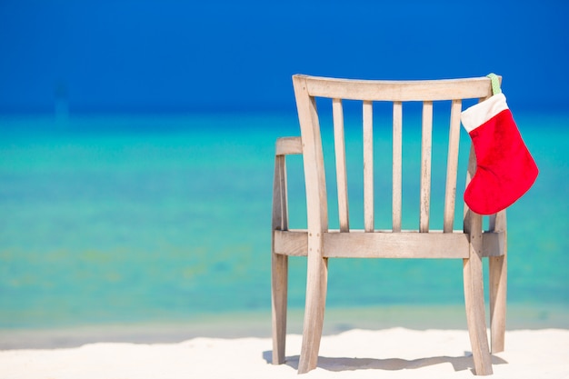 Photo red santa hat on chair at tropical white beach