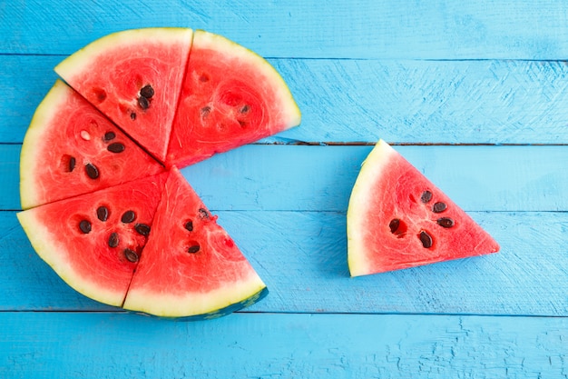 Red scarlet watermelon pieces on blue wooden vintage table