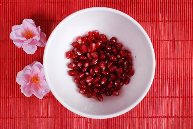 Red seeds of sweet pomegranate in white bowl