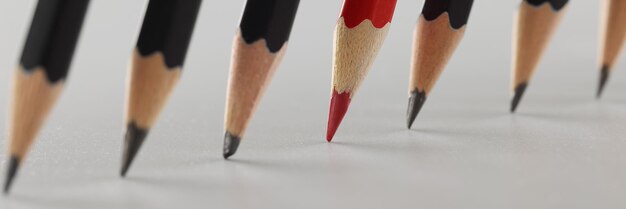 Red sharp pencil among black pencils in a row