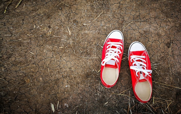 Red shoes white shoelaces on cracked ground