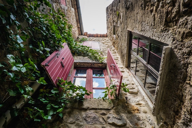 Red shutters, vine and stone facade of a medieval house in the village of Labeaume in Ardeche