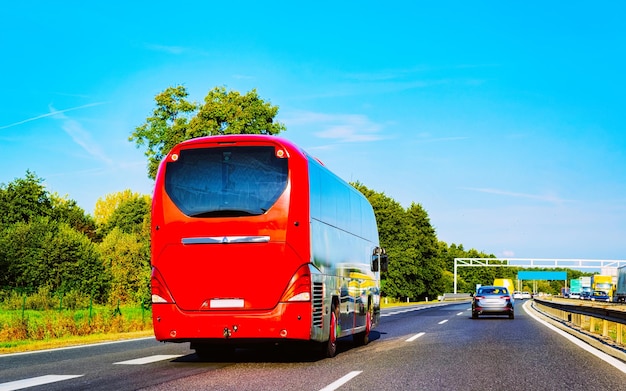 Red Shuttle bus back in road, Poland. Modern public transport traffic and Summer drive. Charter coach vehicle on Vacation trip. Holiday journey for recreation. Motion and urban ride.