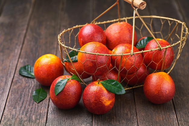 Red sicilian oranges in a metal basket on a wooden table selective focus