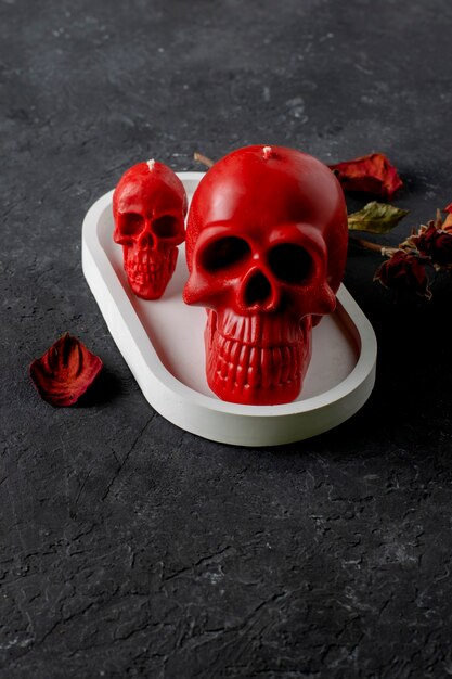 Red skull candles on a concrete stand on a black background.