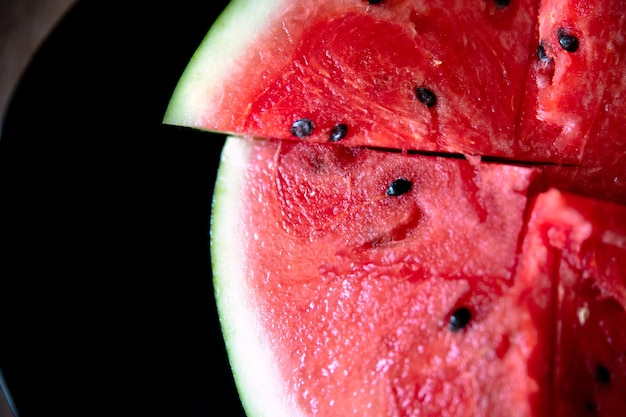 Red sliced watermelon on a black plate