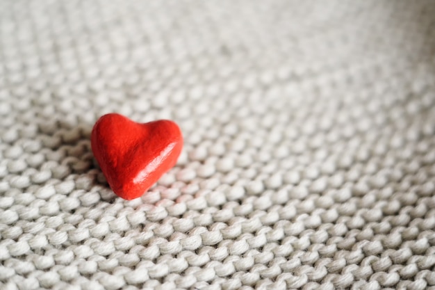 Red small heart on a knitted background close-up. place for text