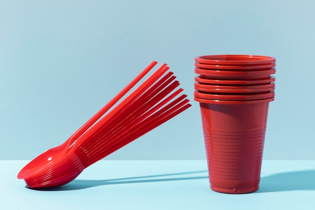 Red small spoons and plastic cups front view