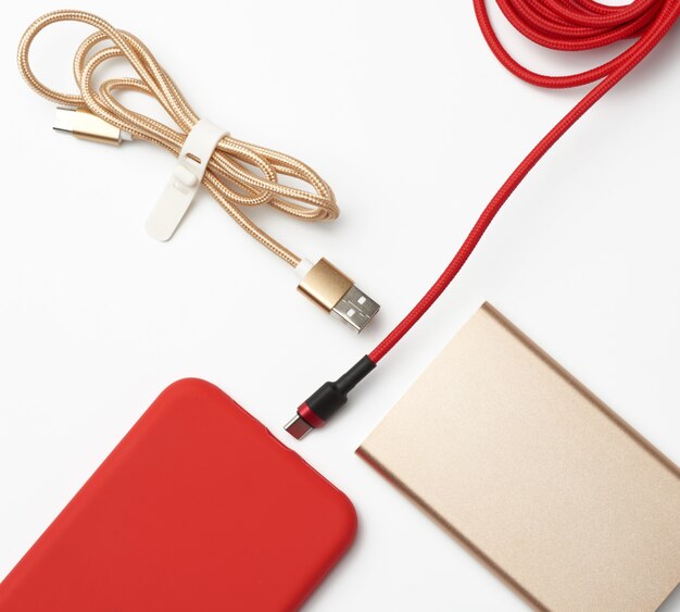 Red smartphone and cable in textile braid on a white space