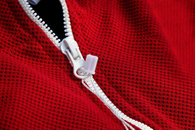 Фото Красная спортивная одежда крупным планом, вид сверху, белая молния, дышащий трикотаж, детали одежды, макро
