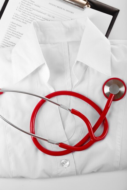 Red stethoscope medical record and uniform close up