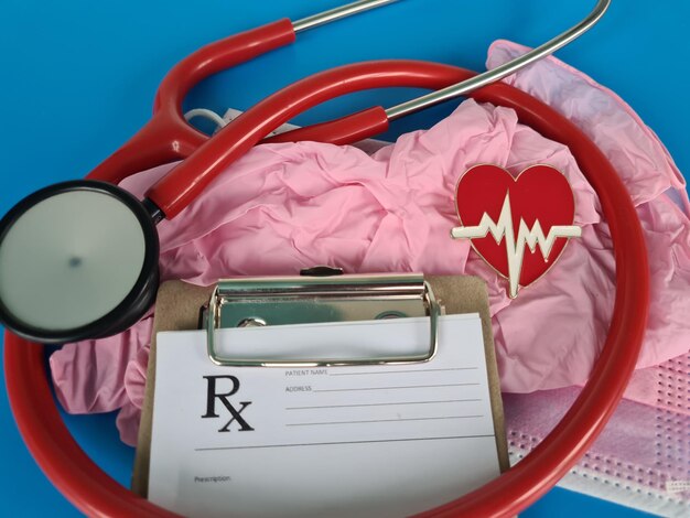 Red stethoscope with pill lie on table against cardiogram bacground closeup