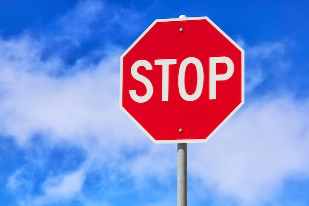 Photo red stop sign against blue cloudy sky background