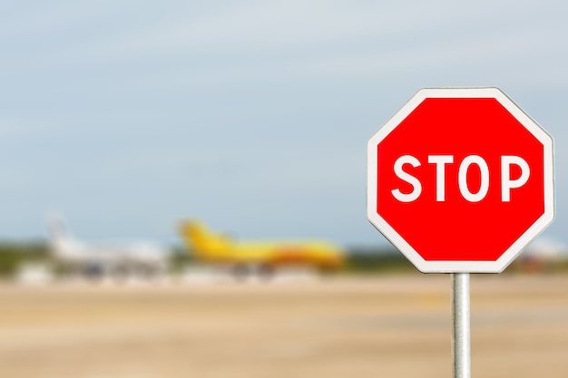 Bluredの赤い停止標識飛行機の飛行機は国際空港に駐車しています