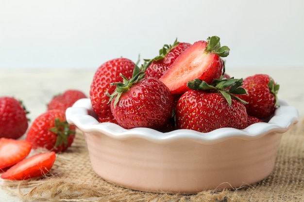 Red strawberries in a ceramic bowl on a light concrete table