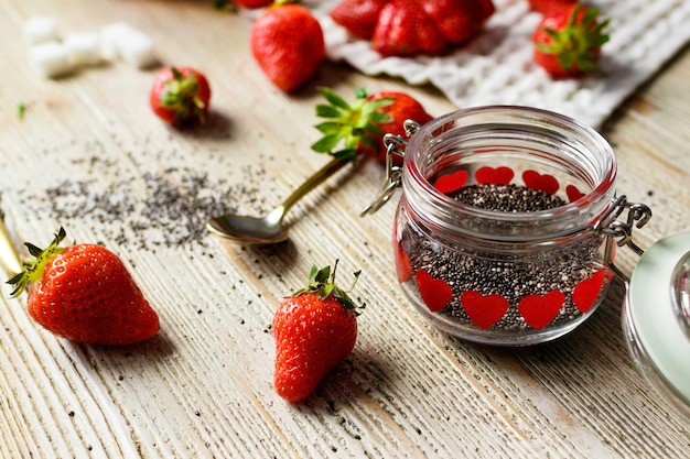 Red strawberries and sugar on a wooden background