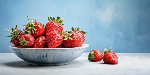 Red strawberries on white plate with blue rim on textured grey background