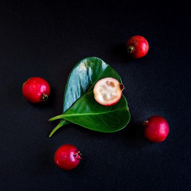 Photo red strawberry guava fruit on black background psidium cattleyanum top view