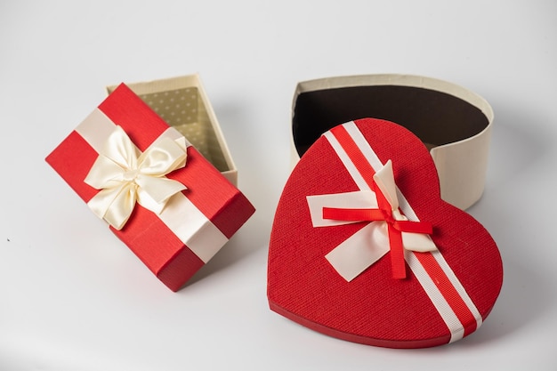 Foto scatole rosse e a righe con regali legati fiocchi su sfondo bianco