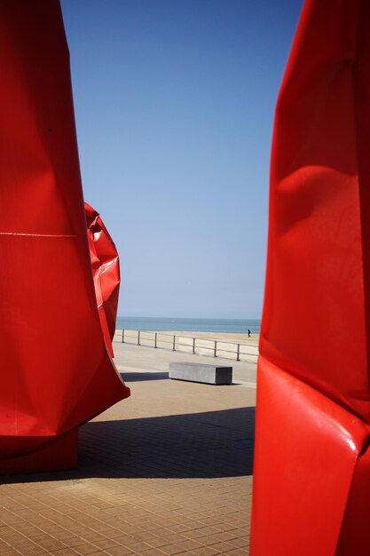 Red structures against sea on sunny day