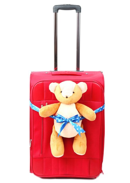 Red suitcase with toy teddy bear isolated on white