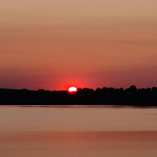 A red sunset is in the sky with the sun setting behind it.