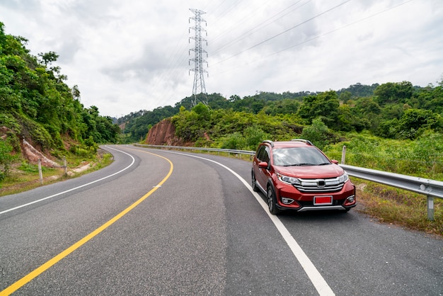 山の緑の森とアスファルトの道路に赤いSuv車