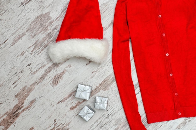 Red sweater and santa hat on a wooden background Fashionable concept