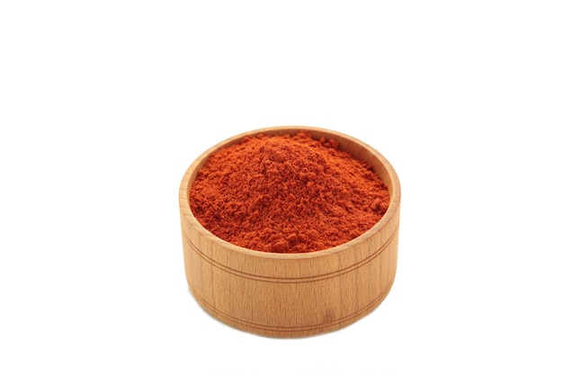 Foto polvere di paprika dolce rossa su piatto su sfondo di ciotola di legno