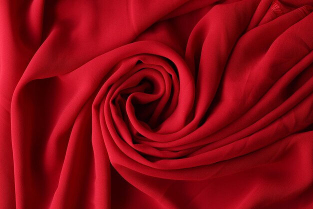 Red swirled fabric as background red wavy textile close up