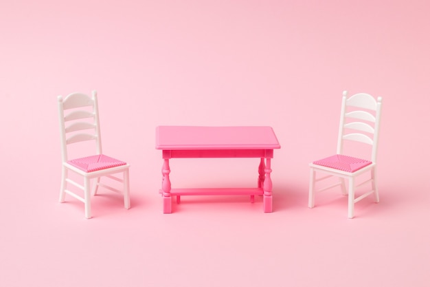 Red table with two chairs on a pink surface