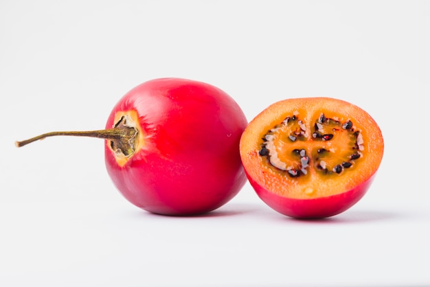 Red Tamarillo with a slice over white background