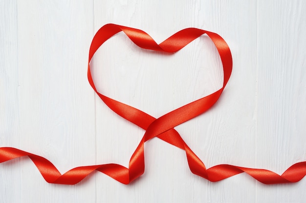 Photo red tape with heart shape on white wooden background for valentine greeting card