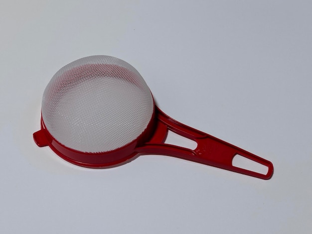 A red tea strainer on isolated background