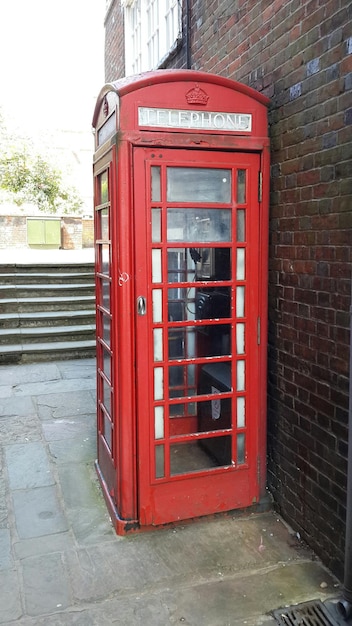 Foto cabina telefonica rossa contro il muro di mattoni