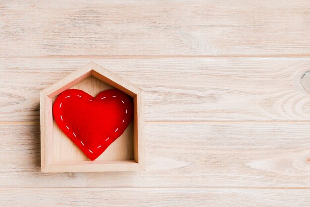 red textile heart in a house on wood