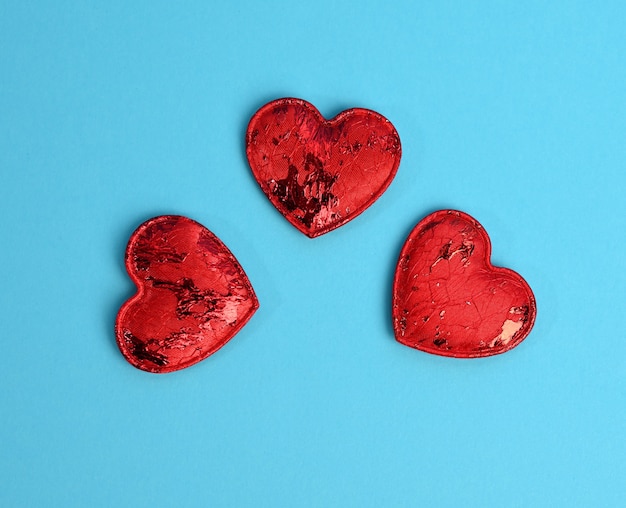 Piccoli cuori tessili rossi su sfondo blu, sfondo festivo, vista dall'alto