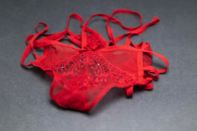 red thong panties with lace on a gray background with blue rhinestones